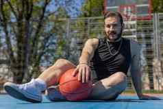 肖像累了微笑运动黎巴嫩男人。运动服装放松玩篮球游戏