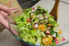 年轻的女人准备健康的蔬菜沙拉烹饪蔬菜沙拉玻璃碗特写镜头表格木勺子