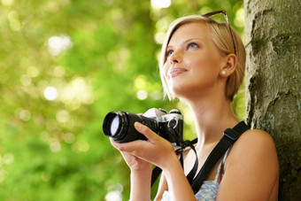 搜索主题可爱的年轻的摄影师持有相机倾斜树