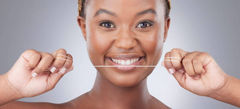 用牙线清洁牙齿有效的改变味道工作室拍摄有吸引力的年轻的女人用牙线清洁牙齿牙齿灰色背景