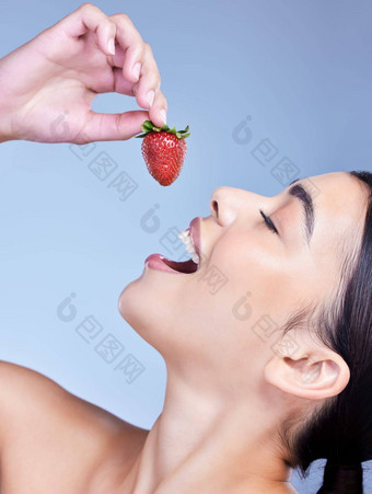 快乐微笑混合比赛女人吃草莓拉美裔模型促进皮肤好处健康的饮食蓝色的Copyspace背景