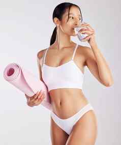 喝水锻炼吃健康的适合年轻的女人持有玻璃水瑜伽席