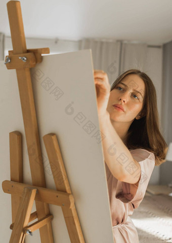 年轻的特写镜头女人艺术家绘画帆布画架首页卧室艺术创造力概念