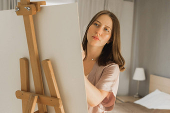 年轻的特写镜头女人艺术家绘画帆布画架首页卧室艺术创造力概念