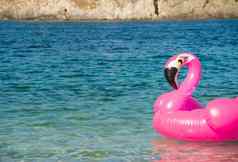 游泳环形状粉红色的火烈鸟水海滩水背景花俏的游泳环夏天假期放松时间