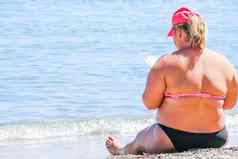女人穿他坐着海滩阅读书盯着海超重女身体海滩大小女人复制空间