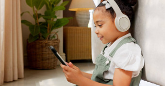 平板电脑游戏耳机放松孩子游戏有趣的玩在线游戏移动设备数字科技应用程序孩子娱乐青年生活方式年轻的玩家女孩玩触屏