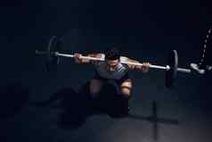 杠铃蹲黑暗健身房男人。体育培训锻炼健身重举重健康俱乐部印度健美运动员运动员身体锻炼肌肉权力强大的动机