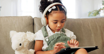 平板电脑游戏耳机放松孩子游戏有趣的玩在线游戏移动设备数字科技应用程序孩子娱乐青年生活方式年轻的玩家女孩玩触屏