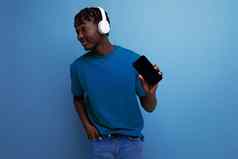 年轻的非洲男人。玩游戏无线耳机移动电话