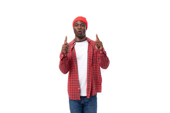 聪明的自信年轻的美国男人。红色的帽格子衬衫手做手势广告白色背景复制空间