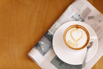 咖啡卡布奇诺咖啡心泡沫报纸表格人餐厅咖啡馆喝爱写作泡沫饮料艺术牛奶咖啡馆特写镜头杯子模型