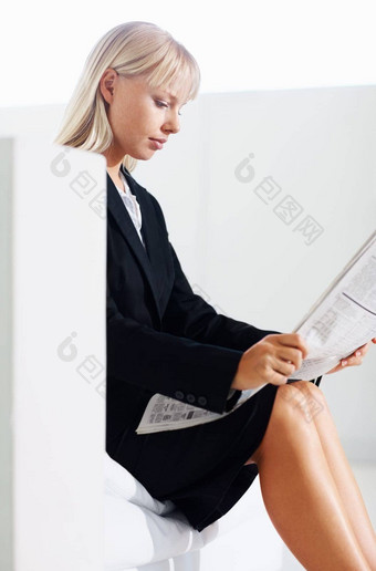 业务女人阅读新闻一边视图年轻的业务女人阅读报纸