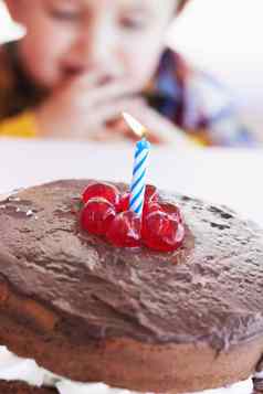 生日蛋糕特写镜头年轻的孩子庆祝活动蜡烛甜点首页孩子巧克力樱桃蜡烛庆祝男孩聚会，派对糖果厨房表格房子