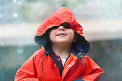 快乐男孩红色的雨衣孩子玩有趣的雨滴在户外微笑孩子天空享受降雨淋浴散景背景
