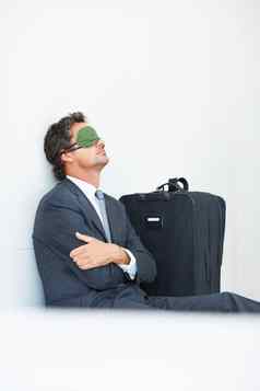 业务男人。睡眠面具成熟的业务男人。睡眠面具坐着墙旅行行李