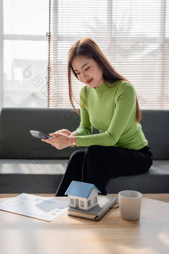 女人坐着舒适的沙发规划计算费用抵押<strong>贷</strong>款计算器首页桌子上保险预算住宅<strong>贷</strong>款住宅业务财产概念