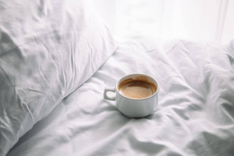 杯咖啡床上白色棉花床上用品早....咖啡概念周日孤独放松舒适情绪极简主义作文光影子白色杯子美国快报