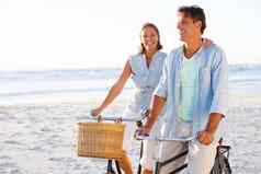 让人耳目一新在户外成熟的夫妇享受自行车骑海滩