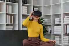 有吸引力的亚洲女人休息舒适的生活房间眼镜放松沙发生活方式虚拟现实耳机