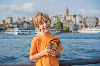 男孩伊斯坦布尔早餐simit玻璃土耳其茶玻璃土耳其茶百吉饼simit金角湾加拉塔塔伊斯坦布尔火鸡突厥语旅行孩子们概念