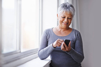 窗口应用程序高级女人智能手机连接打字社会媒体首页成熟的夫人女人模型手机沟通在线阅读发短信