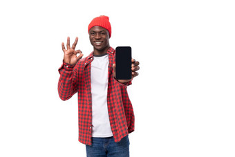 成功的英俊的皮肤黝黑的美国男人。穿着红色的衬衫帽显示智能手机广告白色工作室背景复制空间
