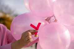 手粉红色的丝带背景粉红色的气球预防周期乳房检查