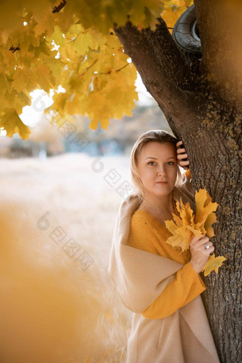 金发女郎站秋天树深思熟虑的女人之前穿着黄色的衣服秋天内容