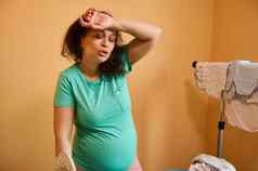 疲惫成人怀孕了女人删除汗水额头感觉过度劳累家庭烦人的事熨斗婴儿衣服