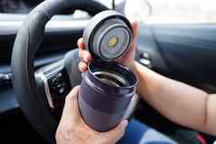 亚洲女人司机持有热杯子热咖啡车危险的风险事故