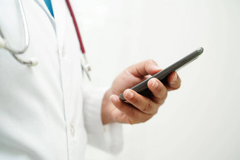 亚洲女人医生持有移动电话平板电脑搜索方法治疗病人医院