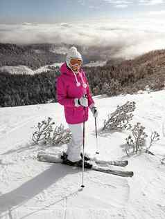 年轻的女人粉红色的夹克滑雪板滑雪波兰人护目镜他摆姿势雪覆盖跑道太阳闪亮的森林