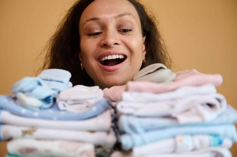 疲惫快乐女人微笑美丽的露出牙齿的微笑持有清洁熨婴儿衣服出生孩子