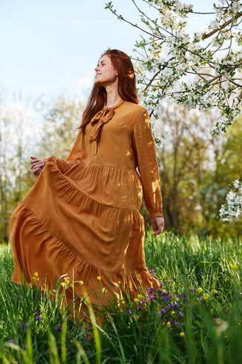 快乐纤细的甜蜜的女人站长橙色衣服高草开花树幸福的微笑电梯他衣服