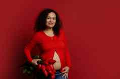 多少数民族怀孕了女人微笑相机持有花束红色的郁金香孤立的颜色背景