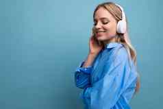特写镜头欧洲女孩无线大耳机休闲装享受放松音乐应用程序蓝色的背景