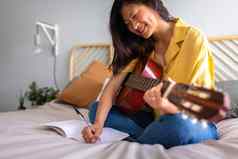 年轻的亚洲女首歌作家作曲首歌卧室写作歌词玩声吉他音乐家