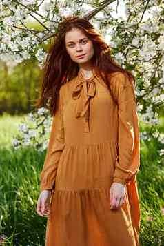 明亮的垂直照片有吸引力的女人长橙色衣服站开花树阳光明媚的温暖的天气愉快地相机