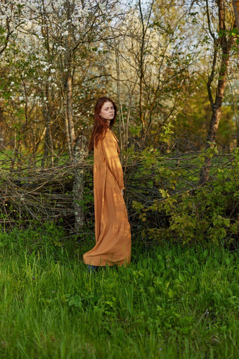 优雅的复杂的女人提出了放松站柳条栅栏别墅长橙色衣服愉快地相机