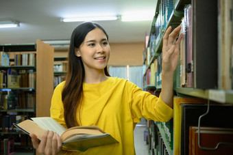 积极的女大学学生选择书架子上研究准备考试大学图书馆教育大学学习