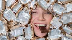 脸高加索人女人包围糖果包装器女孩吃酒吧巧克力