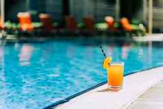 热带闪闪发光的鸡尾酒池拍摄玻璃橙色柠檬水水果鸡尾酒站在游泳池边夏天酒精免费的喝酒店池夏天假期假期