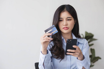 不开心年轻的亚洲女人坐首页手机问题购物在线信贷卡心烦意乱沮丧千禧少数民族女困惑银行错误错误支付互联网