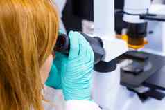 女人科学家执行生物分析观察样品显微镜