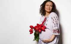 令人愉快的怀孕了女人白色衣服绣花点缀乌克兰风格微笑持有手肚子