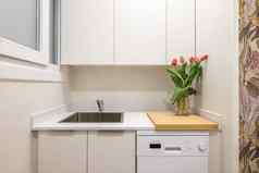 特写镜头水槽厨房表面橱柜花瓶郁金香现代时尚的白色厨房概念时尚的舒适的厨房小公寓Copyspace