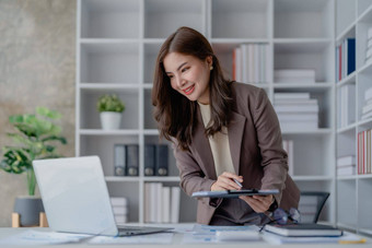 肖像深思熟虑的亚洲女商人金融语句使市场营销计划电脑桌子上