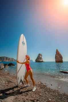 女人冲浪者夏天旅行海滩假期中年女人红色的泳衣帽肉豆蔻背景海岩石水极端的体育运动旅行周末生活方式