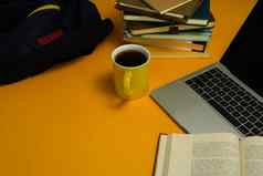 移动PC咖啡杯堆栈书背包黄色的背景在线学习回来学校教育概念